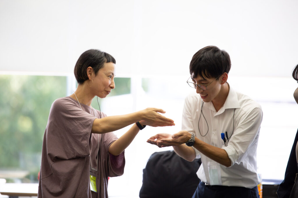 Two participants facing each other in an exercise with raised hands